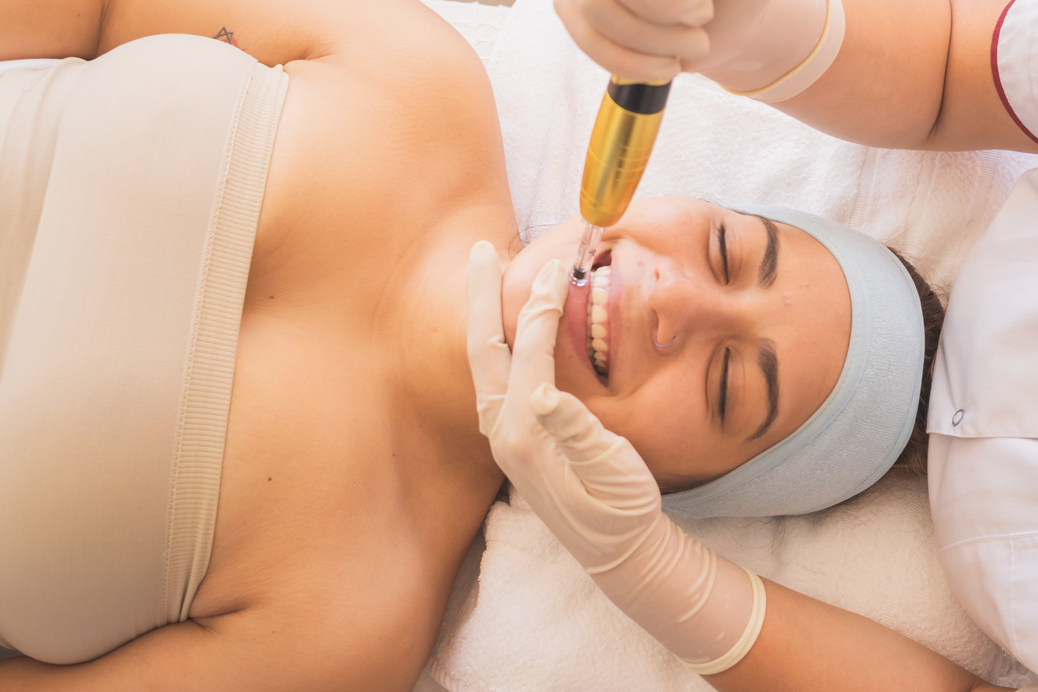 Top view of a beautiful Hispanic woman getting lip microneedling therapy in the spa