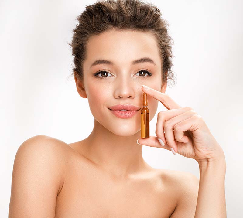 Woman holds ampoule with serum for hair or skin care