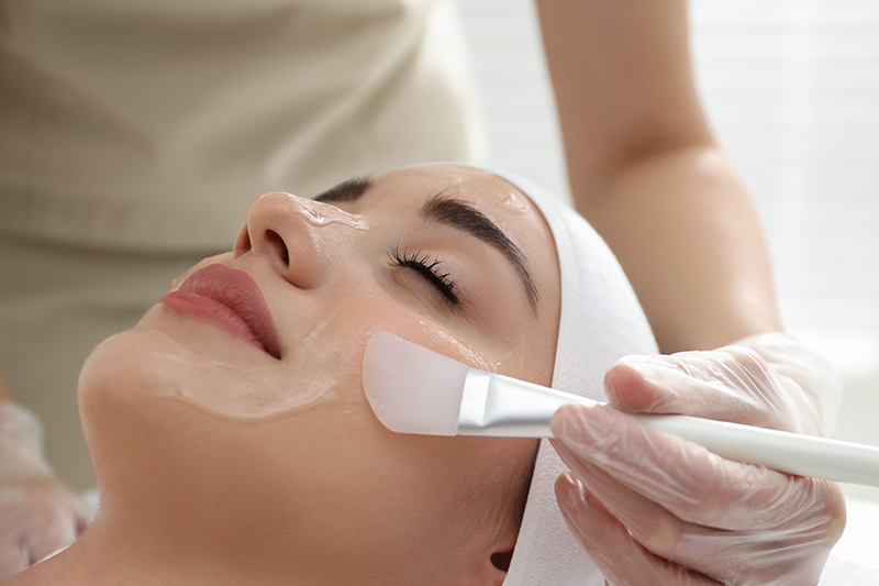 Young woman during face peeling procedure in salon