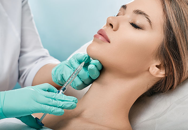 Beautiful woman getting collagen injection into chin