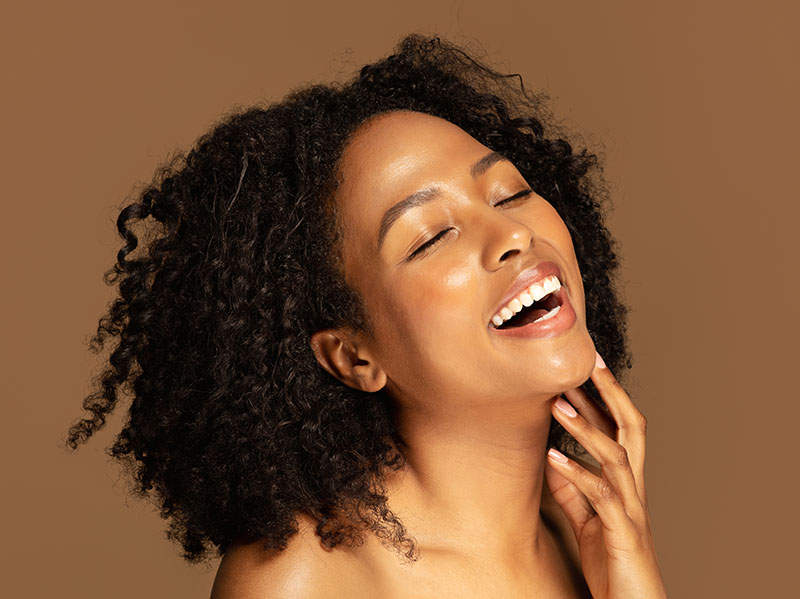 Laughing sensual half-naked black lady touching her chin
