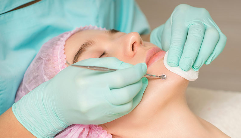 Beautician removing blackhead and acne on female chin